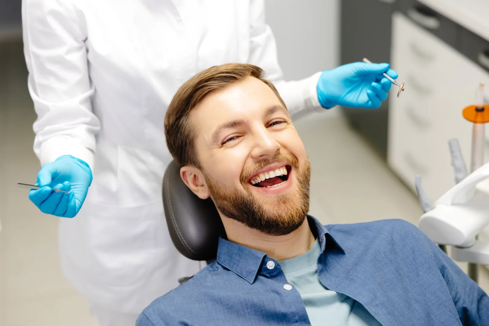 a man is smiling while sitting in a dental chair .