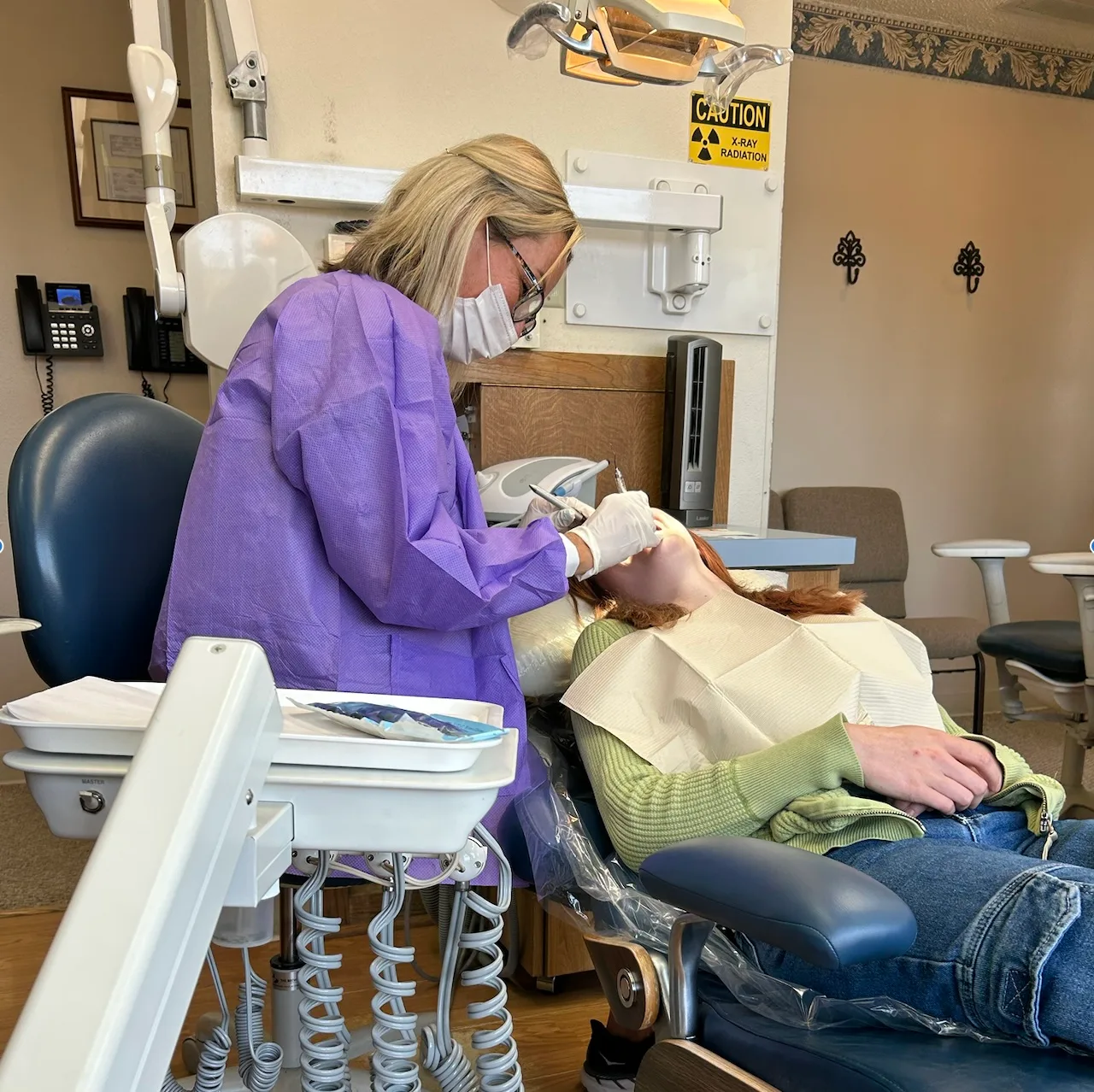 a woman is sitting in a dental chair getting her teeth examined by a dentist .